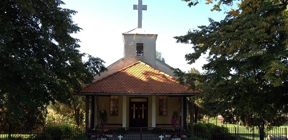 Filijalna kapela Uzvišenja sv. Križa u Dubovici, mala kapela s drvenim trijemom i križem na vrhu, okružena drvećem.